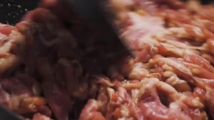生猪肉在平底锅上炒。宏观拍摄。准备制作炒菜菜单。