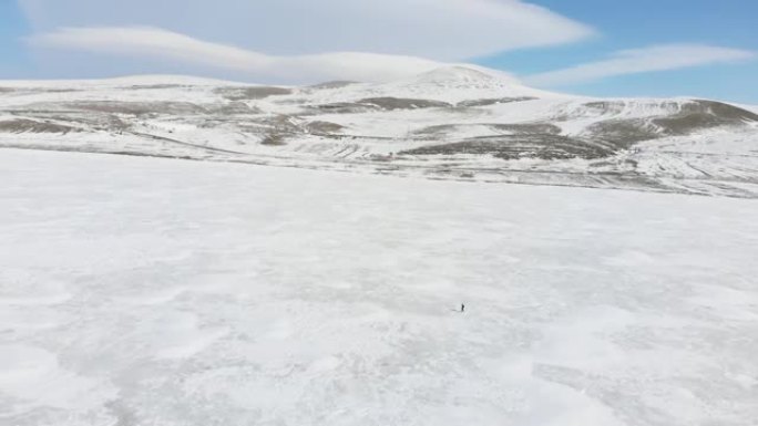 鸟瞰图独自一人在冰湖上行走，从空中视角看雪景背景