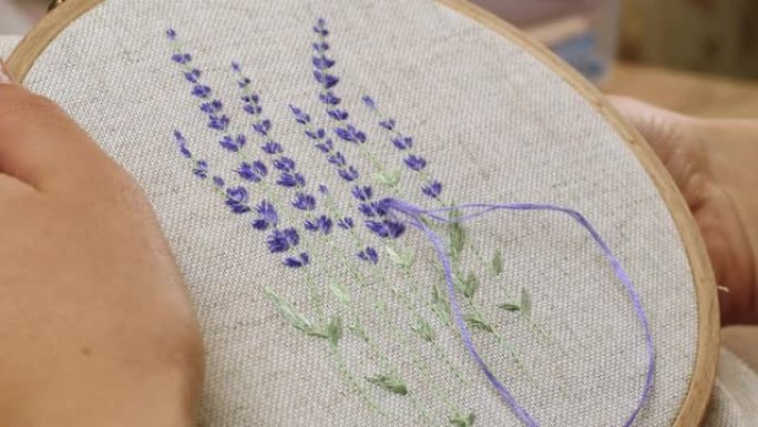 女人在亚麻织物上绣花非常漂亮的薰衣草花。手工embr