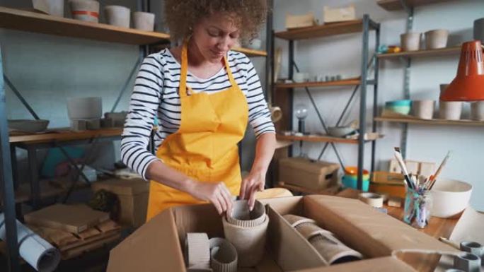 Craftwoman将混凝土锅包装在盒子中，以交付给客户