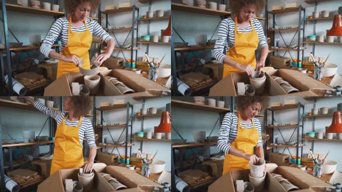 Craftwoman将混凝土锅包装在盒子中，以交付给客户