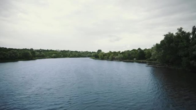 河上的日落。鱼跳出水面。岸边有绿树的平静湖的风景。