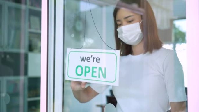 戴口罩的悲伤女人在一家门店从开门转到关门，小店生意后新型冠状病毒肺炎检疫封锁。