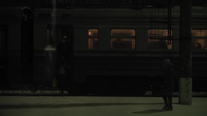 交通、公路、铁路、景观、交通、概念 -- 夜幕下在火车站上车的人的窗口视图。在下雪的冬天乘火车在乡村