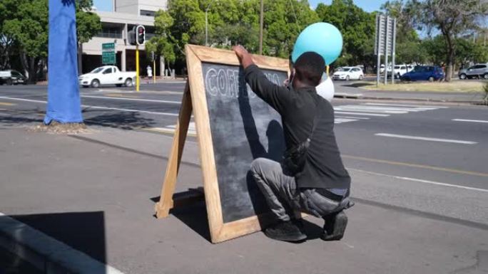 服务员在街上的一块黑板上写字