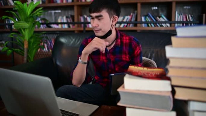 男人和笔记本电脑在图书馆里工作成功，享受他们的辛勤工作。