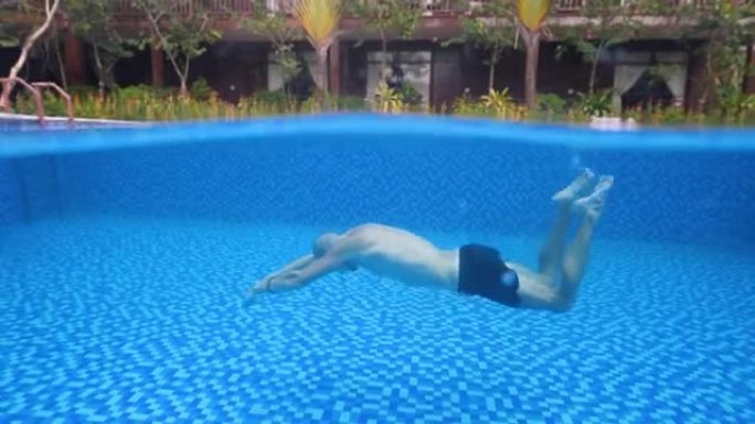 一个男人在游泳池里像美人鱼一样游泳的水下照片。