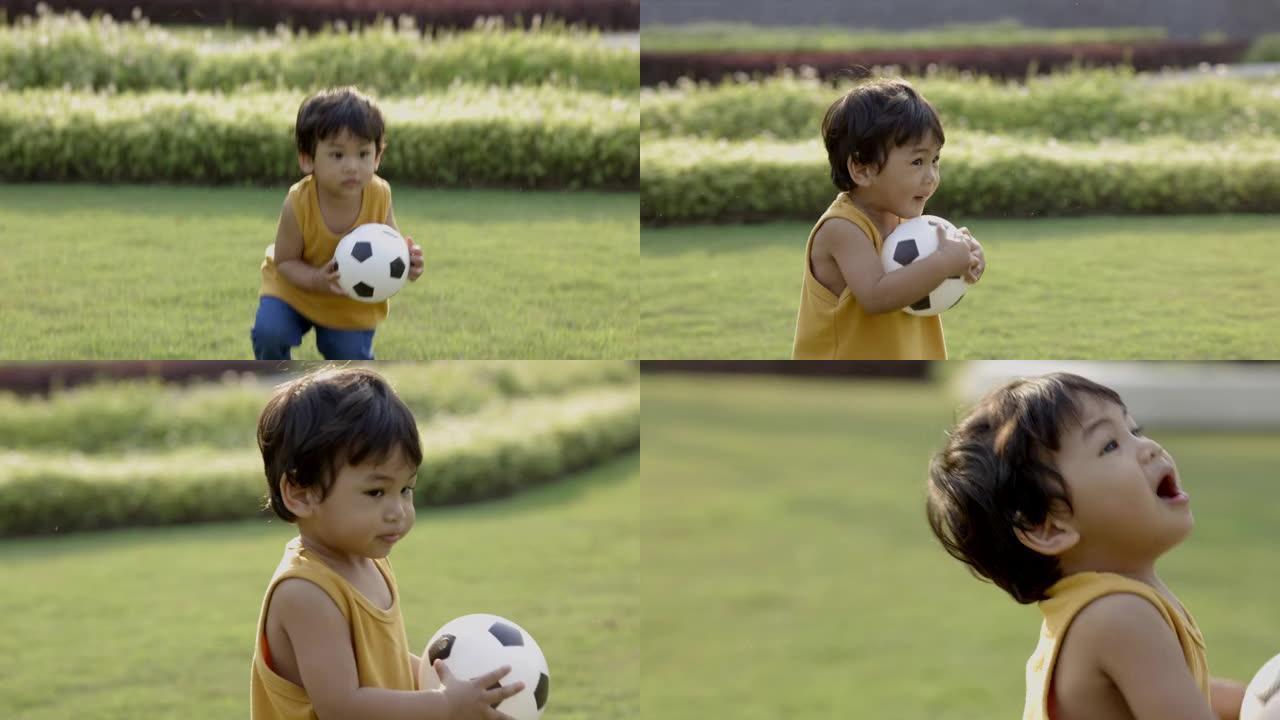 亚洲小男孩穿着黄色衬衫，在草坪中央踢足球。