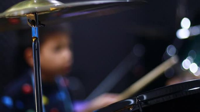 模糊的孩子在音乐室学习和演奏鼓。乐器的概念。