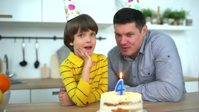 非常可爱的男孩用蛋糕和快乐的父亲庆祝他的生日。4年生日快乐。父亲节。小男孩在家吹灭生日蛋糕上的蜡烛