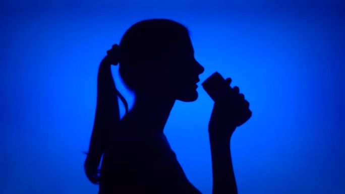 蓝色背景上的女人打开软饮料的轮廓。轮廓饮料苏打水中的女性脸