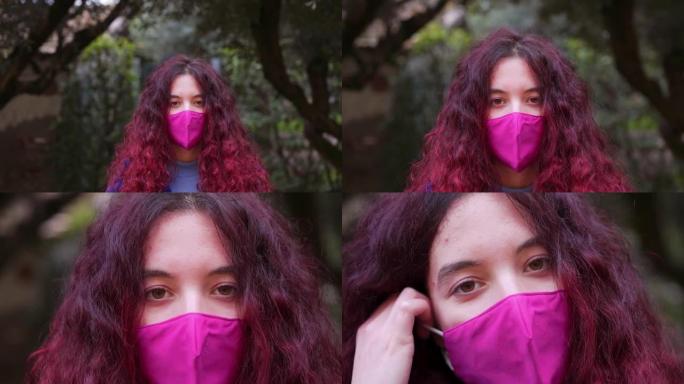 一名年轻女子的追踪镜头取下了她的面具，以保护自己免受病毒侵害，并对着镜头微笑。慢动作镜头