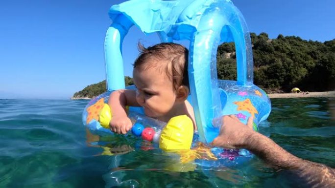 快乐的女婴漂浮在海上充气床垫上