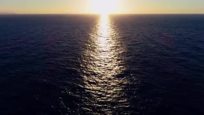 帆船在夕阳下的海中航行。我们可以看到整个地平线上的船和水以及水中光线的反射4K