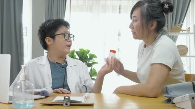 亚洲医生男孩在家里给病人药瓶，呆在家里的概念。