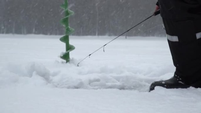 冬季冰上钓鱼。男子在冰洞里摇晃诱饵。在野外放松