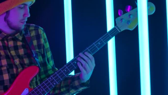 这个人弹吉他。霓虹灯中吉他手指法弦的手的特写。摄像机从吉他手的手到他的脸。慢动作
