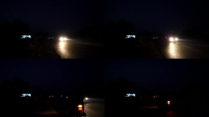 车辆通过黑色柏油路的夜间镜头。前灯从公路驶来的车队。