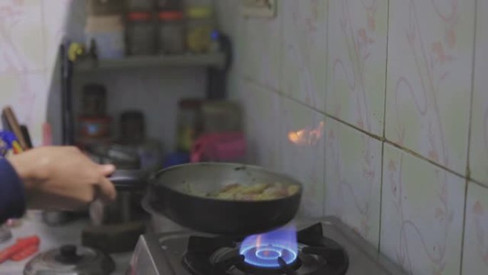 厨师在厨房里翻转热煎锅，在锅里点火。特写。