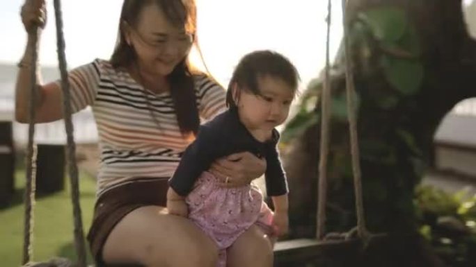 亚洲奶奶带着一个小女孩在秋千上玩耍