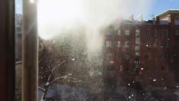 从窗户看到的落雪，它被倾倒，从屋顶清除。雪在阳光下闪闪发光