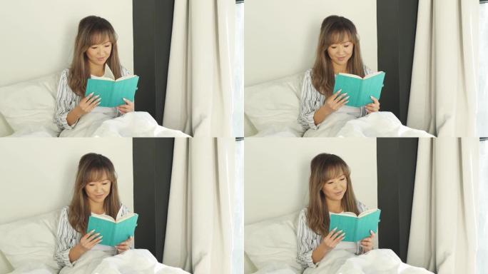 睡个好觉，心情愉快的日本妇女坐在床上穿着睡衣阅读日记或书籍