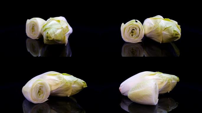 菊苣沙拉在4k的黑色背景上旋转。新鲜比利时菊苣的特写镜头。