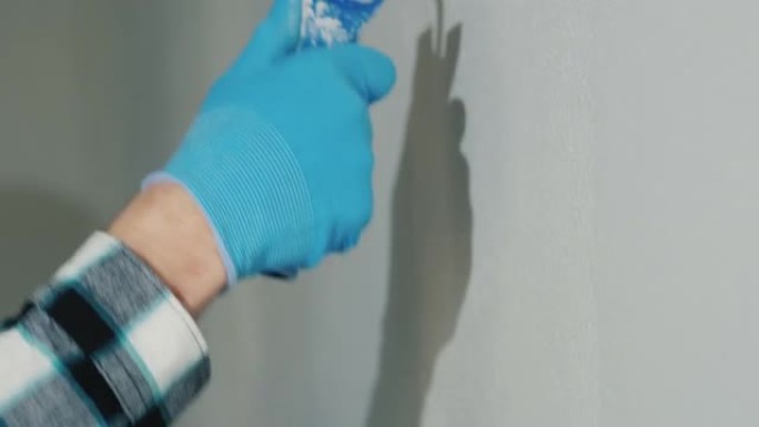 一名工人用滚筒粉刷墙壁，特写镜头