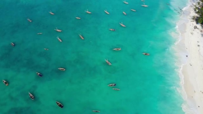从绿松石水面上方看4k飞行无人机，上面有白沙和渔船。旅游、渔业、热带概念。坦桑尼亚基翁瓦海滩桑给巴尔