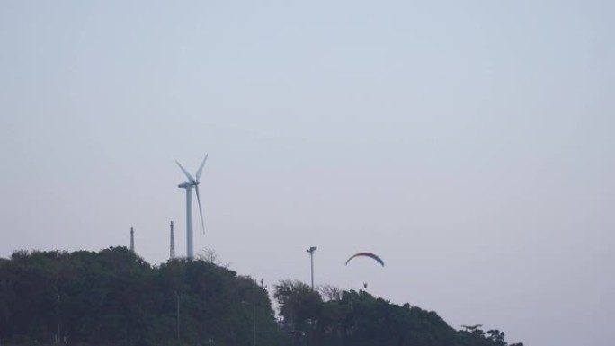 动力伞在风车旁边飞行。
