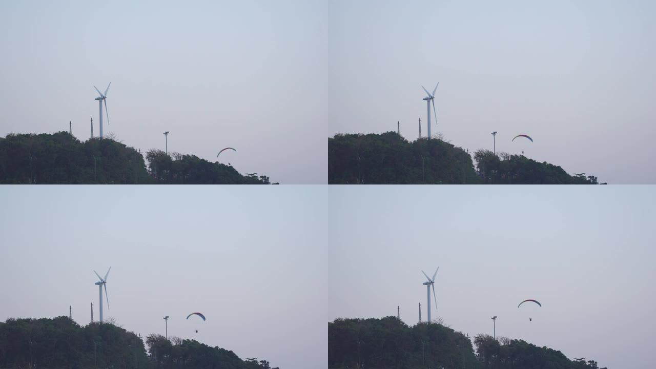 动力伞在风车旁边飞行。