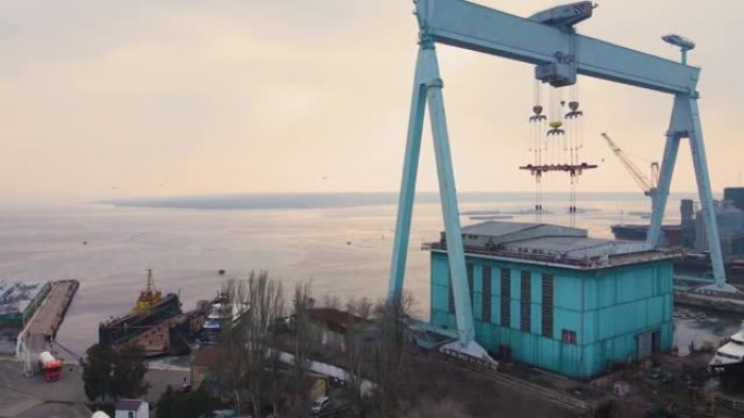 大型货运起重机在国际港口商业码头的造船厂配备金属粮仓，并将游艇停泊在融冰的水中