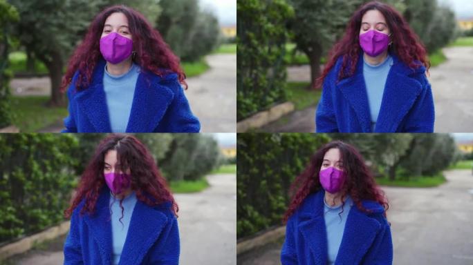 戴着防护面具的年轻女子在街上快乐地行走。慢动作镜头