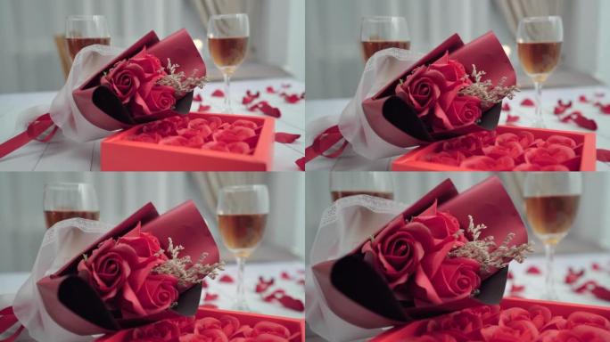 一束鲜花，盒子里的玫瑰躺在浪漫晚餐的桌子上，两杯酒。