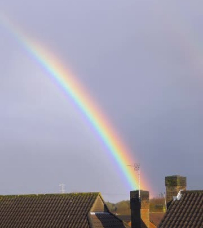 喜怒无常的阴天，房子屋顶上美丽的彩虹，垂直镜头