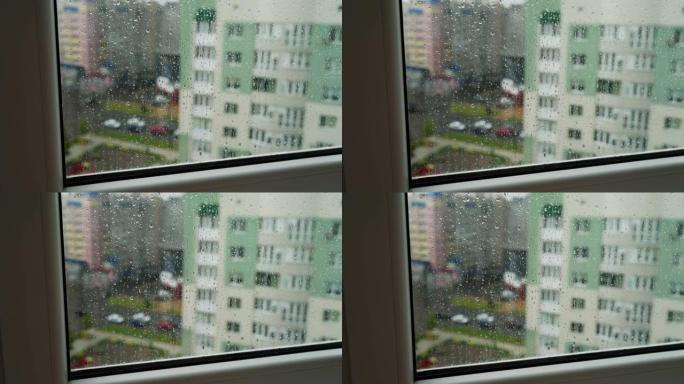 雨滴在窗户玻璃上观看城市景观。带有建筑物背景的窗玻璃上的雨滴。窗户上下雨的风景。