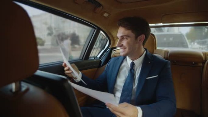 微笑的男性专业人士为商务车文书工作的良好记录而欢欣鼓舞。