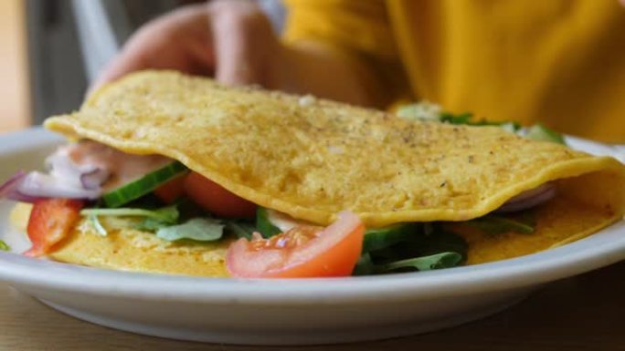 关闭鹰嘴豆煎蛋卷塞满蔬菜。健康的有机素食早餐