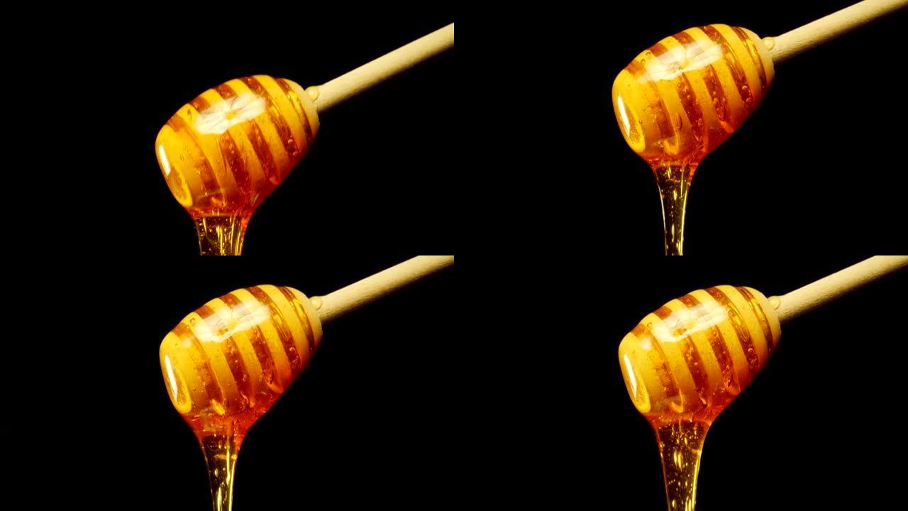 黑色背景上的木制蜜勺滴下蜂蜜。特写。