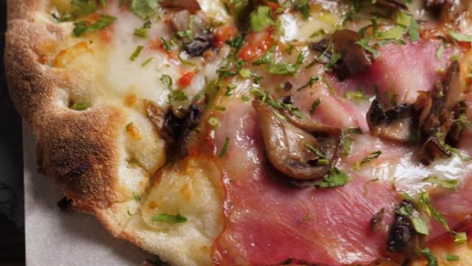 黑色石板拼盘和木桌上一个蘑菇和培根比萨饼