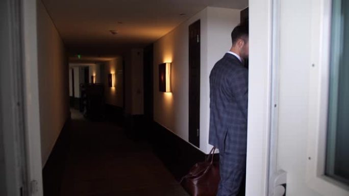 男子走在酒店走廊和开放房间