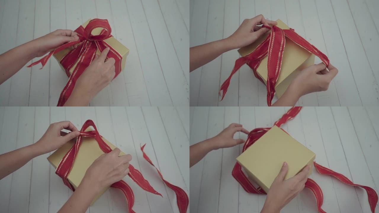 慢动作手女孩解开蝴蝶结打开礼品盒。