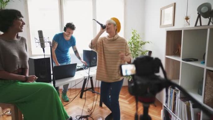 三位年轻艺术家在家庭音乐工作室用相机为他们的新歌录制视频