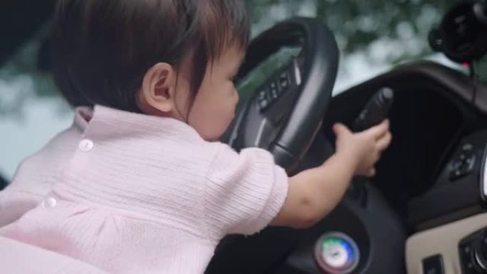 可爱的亚洲女性蹒跚学步坐在汽车驾驶员前排座位上玩方向盘童年的回忆和好奇心快乐快乐的孩子学习技巧经验纯
