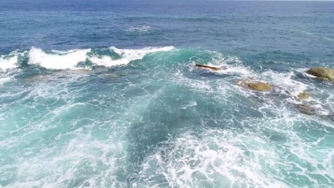 大浪在蓝色海洋中的岩石上断裂的鸟瞰图美丽的热带海洋上有海浪无人机摄像机4k拍摄鸟瞰海浪从上方撞击空石