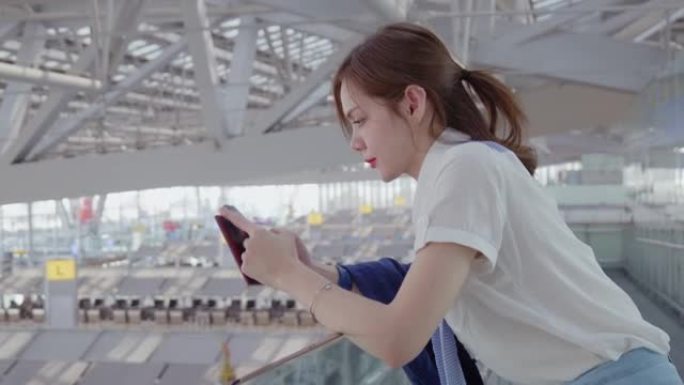20-30岁的亚裔女性在新型冠状病毒肺炎下的机场旅行中使用智能手机穿着休闲服，冠状病毒封锁后的新的正