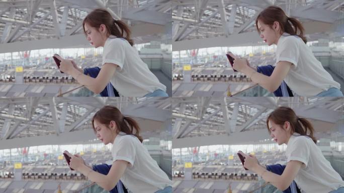 20-30岁的亚裔女性在新型冠状病毒肺炎下的机场旅行中使用智能手机穿着休闲服，冠状病毒封锁后的新的正