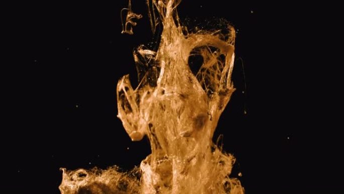 用高速相机拍摄水中金色墨水。金滴的油漆掉落，发生反应，在黑色上形成抽象的云层变形。艺术背景。