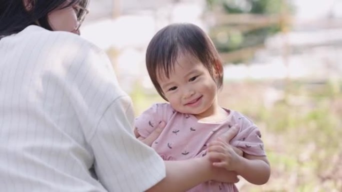 可爱的亚洲女孩和妈妈一起玩，家人在公园里共度时光，可爱的女婴好奇，享受时光，孩子们的情感行为，微笑着