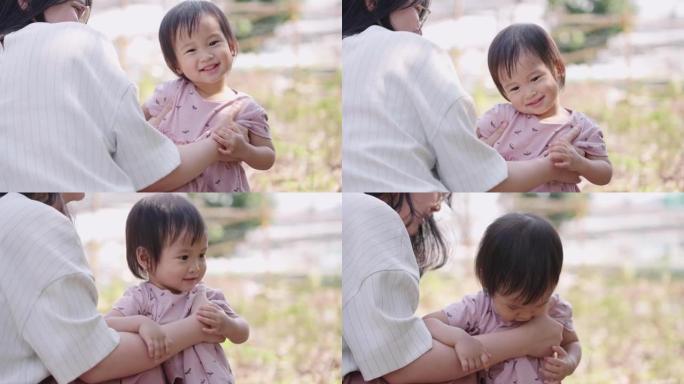 可爱的亚洲女孩和妈妈一起玩，家人在公园里共度时光，可爱的女婴好奇，享受时光，孩子们的情感行为，微笑着